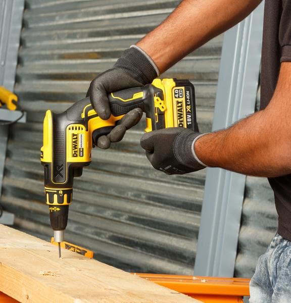 Personne utilise un tournevis sans fil DEWALT DCF620NT-XJ sur du bois en portant des gants.