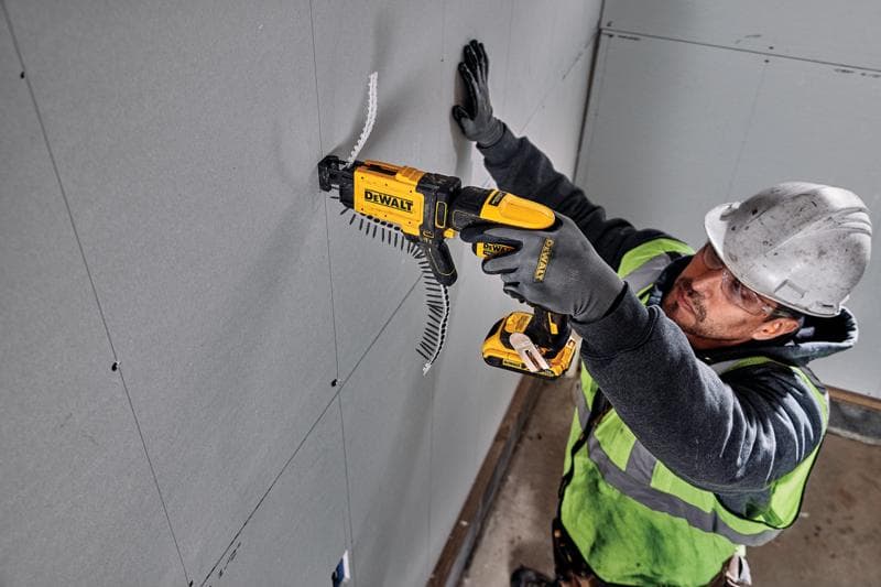 Personne utilisant une visseuse DEWALT DCF6202 pour fixer des panneaux de placoplâtre. Visage flouté.
