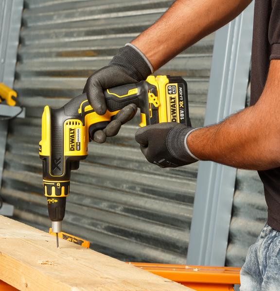 Personne utilise un tournevis sans fil DEWALT DCF620NT-XJ sur du bois en portant des gants.