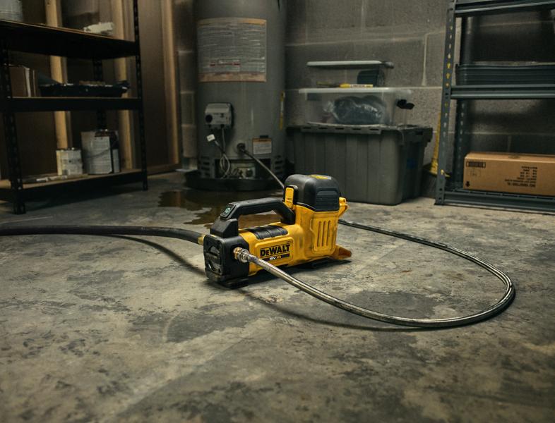Outil DEWALT DCE050N catégorie photographie posé au sol, connecté à un tuyau, entouré d’étagères.